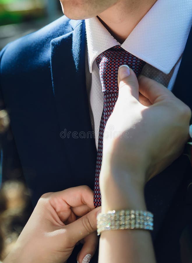 De bruid maakt recht om zijn band, close-up van handen te verzorgen stock foto De bruid maakt recht om zijn band, close-up van handen te verzorgen stock foto