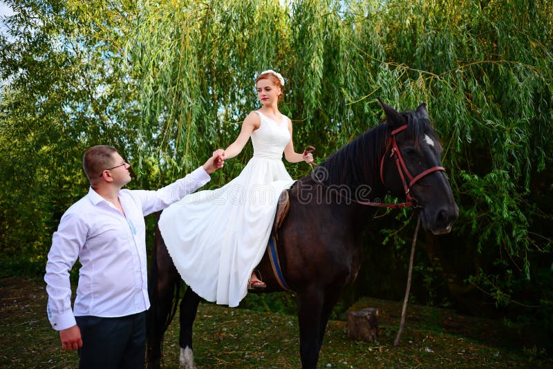 De bruidegom leidt het paard door de teugel De bruid zit in saddl royalty-vrije stock foto De bruidegom leidt het paard door de teugel De bruid zit in saddl royalty-vrije stock foto