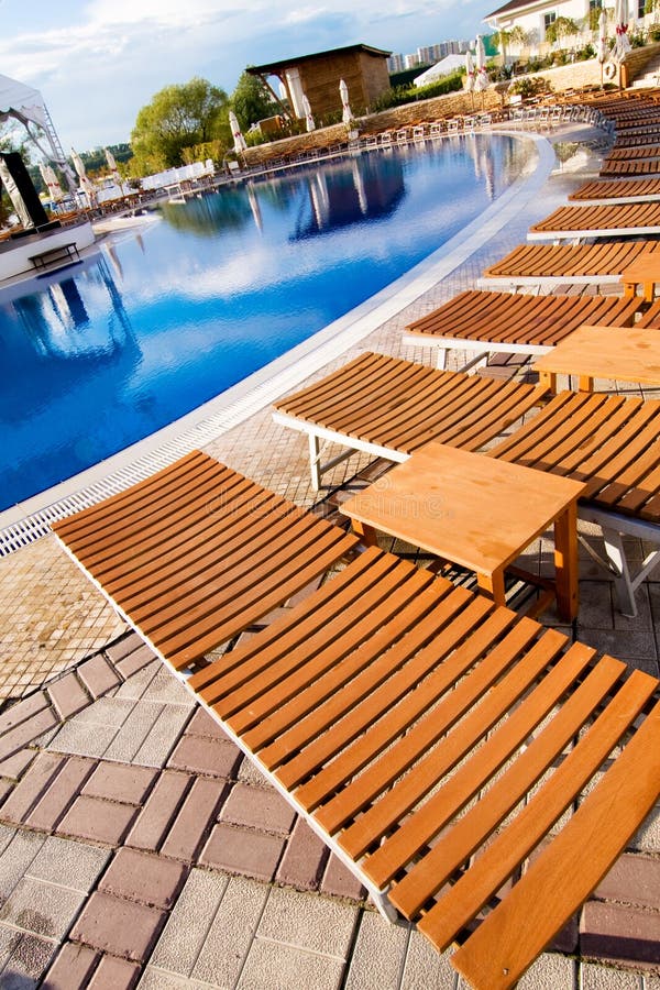 De chaise zitkamer kost dichtbij mooie pool stock foto De chaise zitkamer kost dichtbij mooie pool stock foto