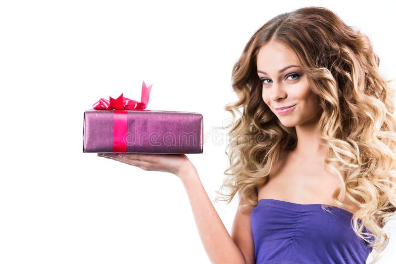 De charmante vrouw met lang krullend haar houdt een gift op een witte achtergrond stock fotografie De charmante vrouw met lang krullend haar houdt een gift op een witte achtergrond stock fotografie