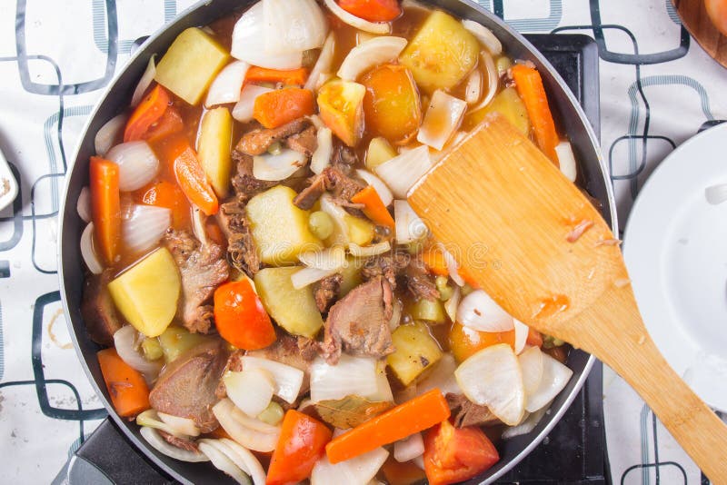De chef-kok beweegt de tonghutspot van het gebraden gerechtvarkensvlees in pan stock afbeeldingen De chef-kok beweegt de tonghutspot van het gebraden gerechtvarkensvlees in pan stock afbeeldingen