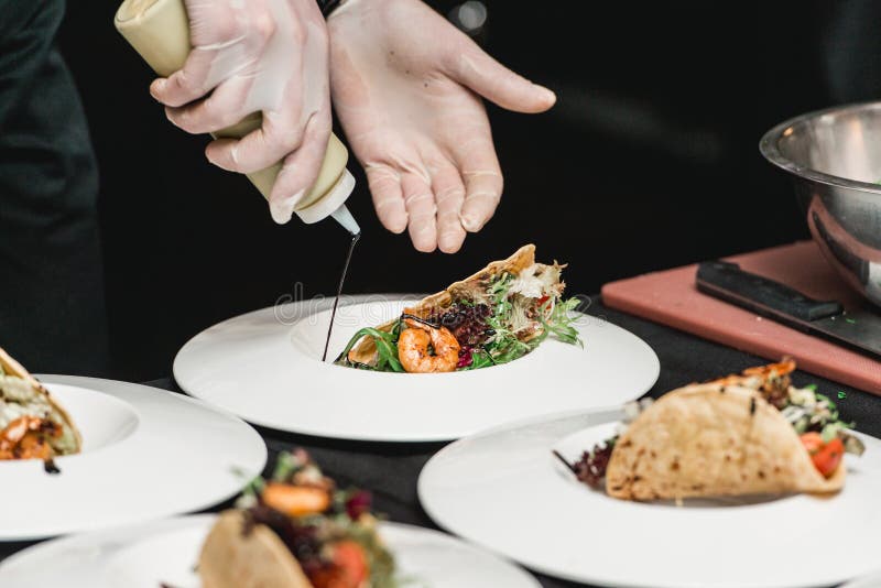 De chef-kok bij het restaurant die Kruidige Garnalentaco's met Koolsla en Salsa maken royalty-vrije stock foto's De chef-kok bij het restaurant die Kruidige Garnalentaco's met Koolsla en Salsa maken royalty-vrije stock foto's