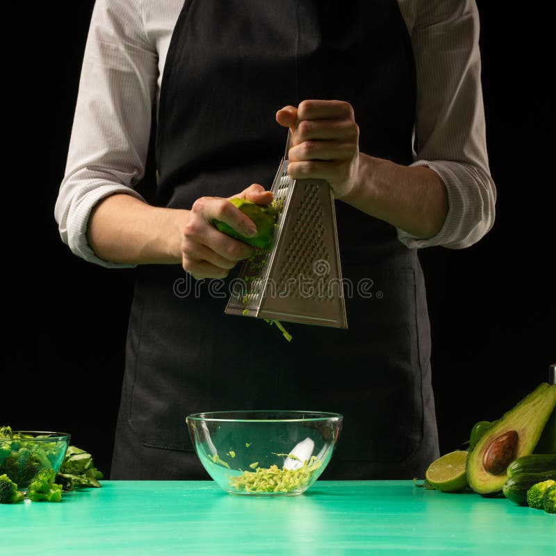 De chef-kok op een zwarte achtergrond wrijft avocado voor het koken van groene detox smoothie Gezond, schoon voedsel, het concept stock foto De chef-kok op een zwarte achtergrond wrijft avocado voor het koken van groene detox smoothie Gezond, schoon voedsel, het concept stock foto