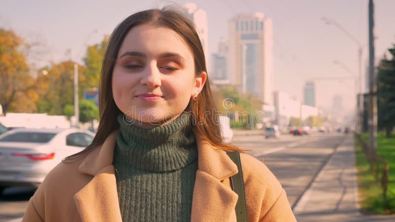 Is de close-up vrij Kaukasische vrouw rechtmaakt haar haar en het glimlachen met natuurlijk gezicht bij camera terwijl status op