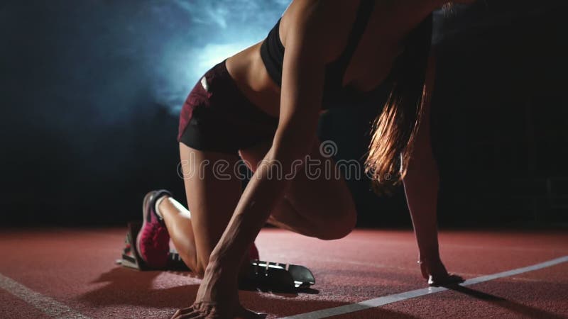 De close-upbenen in tennisschoenenatleten stellen stootkussens op het spoor van de complexe sporten in werking en lopen in langza