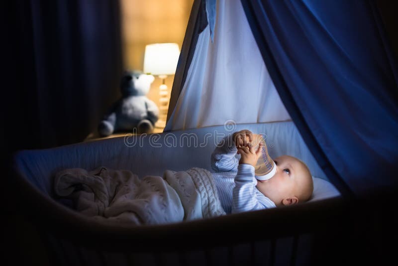 De consumptiemelk van de babyjongen in bed royalty-vrije stock afbeeldingen De consumptiemelk van de babyjongen in bed royalty-vrije stock afbeeldingen
