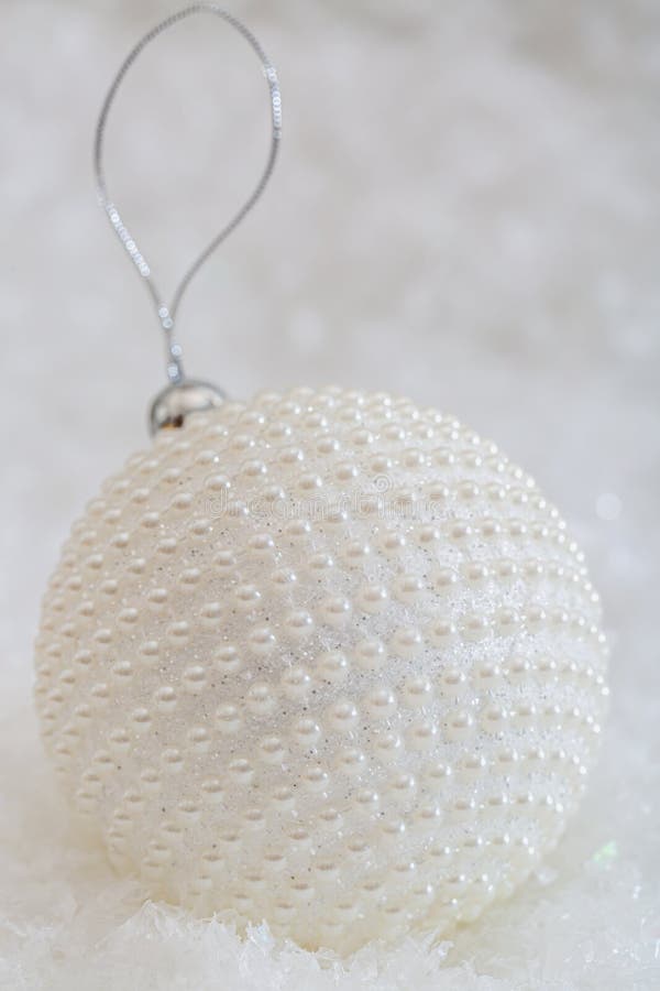 De decoratie van Kerstmis De witte parels van het balpaarlemoer op een sneeuw en een mooie vage achtergrond van het schitteren bo royalty-vrije stock afbeeldingen De decoratie van Kerstmis De witte parels van het balpaarlemoer op een sneeuw en een mooie vage achtergrond van het schitteren bo royalty-vrije stock afbeeldingen