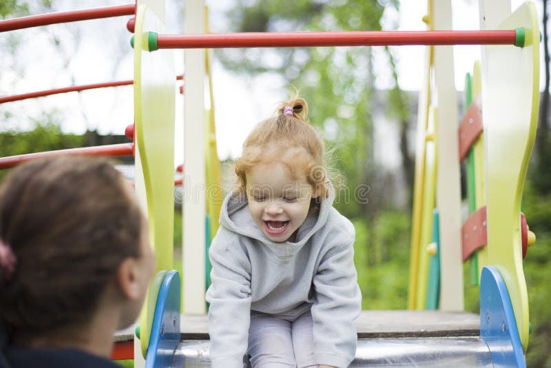 De dochter van moedervangsten van een kinderendia, stelde tevreden dochter op een kinderenspeelplaats tevreden stock afbeeldingen De dochter van moedervangsten van een kinderendia, stelde tevreden dochter op een kinderenspeelplaats tevreden stock afbeeldingen