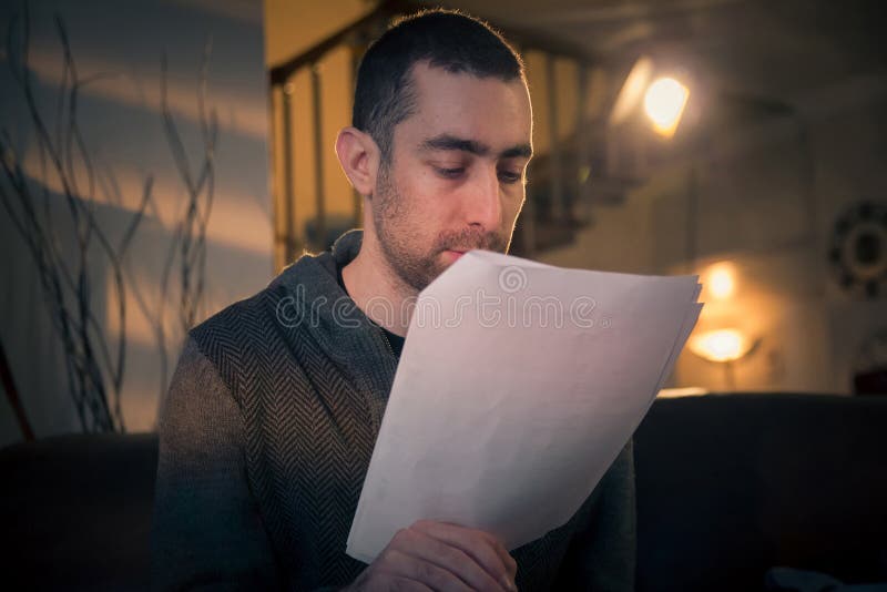 De documenten van de mensenlezing terwijl het zitten op een bank in de ruimte royalty-vrije stock afbeelding De documenten van de mensenlezing terwijl het zitten op een bank in de ruimte royalty-vrije stock afbeelding