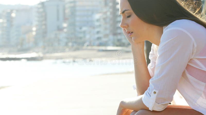 De droevige vrouw klaagt op het strand