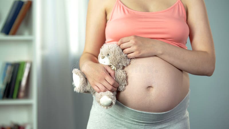 De dromerige vrouw die met zwangere buik stuk speelgoed koesteren draagt teder, leenmoeder royalty-vrije stock foto's De dromerige vrouw die met zwangere buik stuk speelgoed koesteren draagt teder, leenmoeder royalty-vrije stock foto's