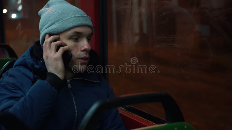 De eenzame jonge mensenritten in een tram en spreekt op de telefoon in de nacht