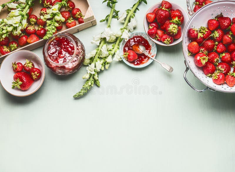 De eigengemaakte smakelijke aardbeienjam in glaskruik met de zomer bloeit en verse bessen, kommen en lepel op lijstachtergrond, h royalty-vrije stock afbeelding De eigengemaakte smakelijke aardbeienjam in glaskruik met de zomer bloeit en verse bessen, kommen en lepel op lijstachtergrond, h royalty-vrije stock afbeelding