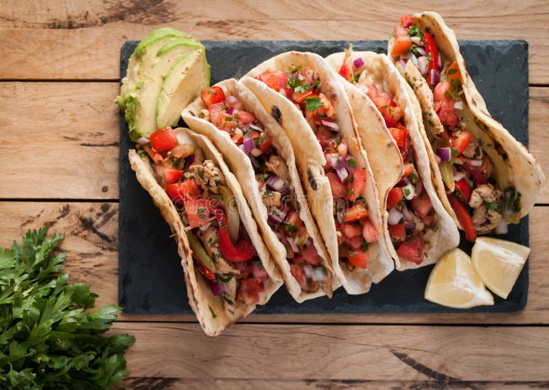De eigengemaakte tortilla's met kruidige kip, groenten en salsa dompelen op houten lijst, hoogste mening onder stock afbeeldingen De eigengemaakte tortilla's met kruidige kip, groenten en salsa dompelen op houten lijst, hoogste mening onder stock afbeeldingen