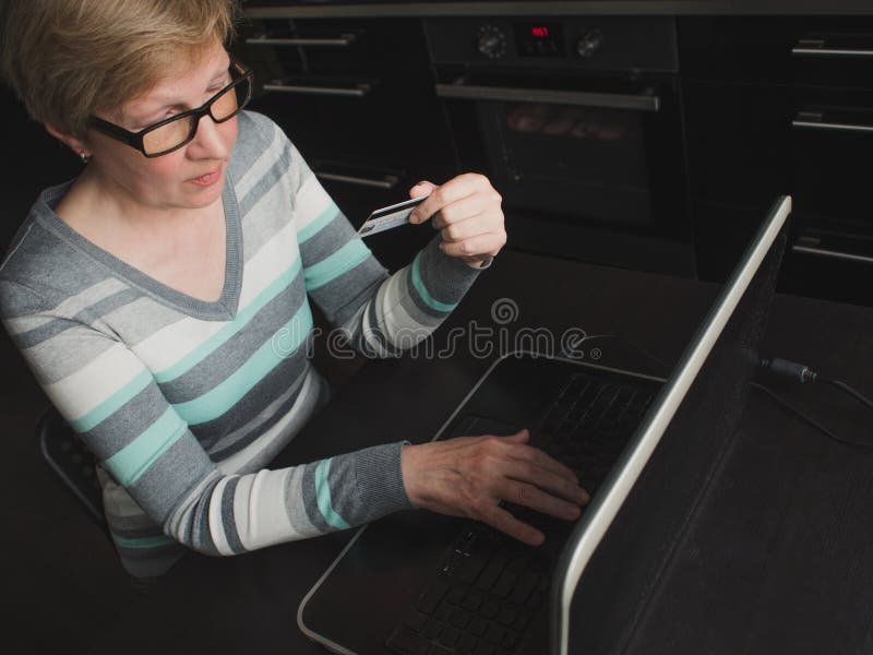 De elegante rijpe vrouw gebruikt Betaalpas voor online betalingen stock foto's De elegante rijpe vrouw gebruikt Betaalpas voor online betalingen stock foto's