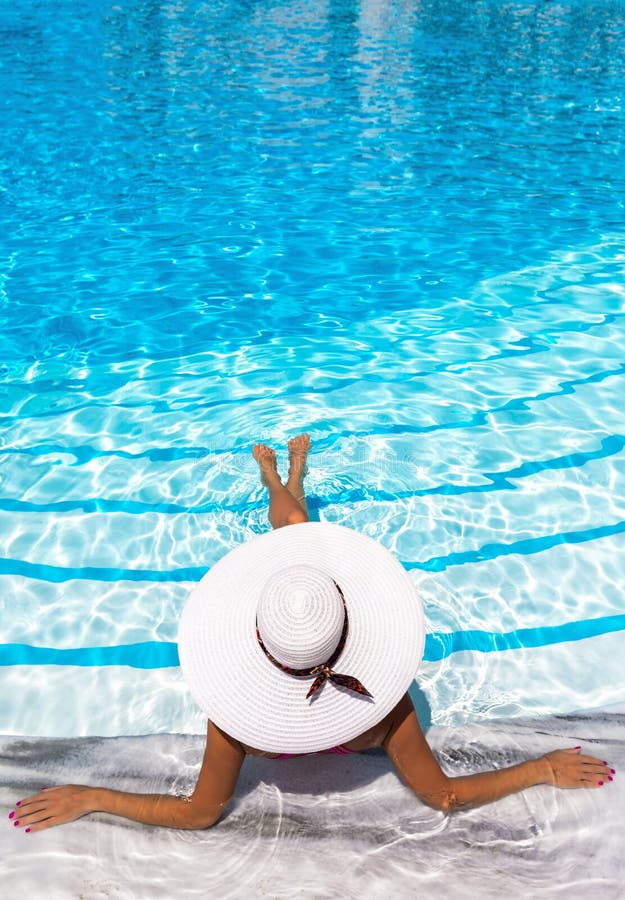 De elegante vrouw met witte hoed geniet van de pool stock foto's De elegante vrouw met witte hoed geniet van de pool stock foto's