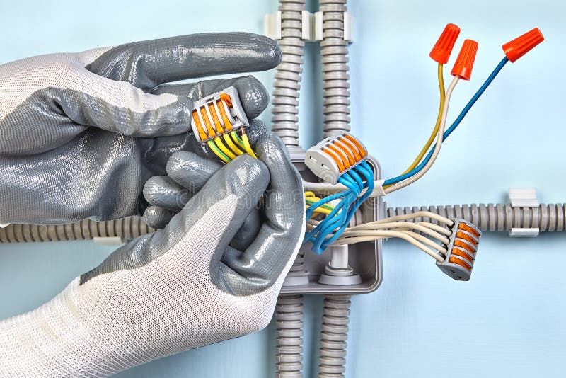 De elektricien in beschermende handschoenen zet kabeldoos op stock foto De elektricien in beschermende handschoenen zet kabeldoos op stock foto