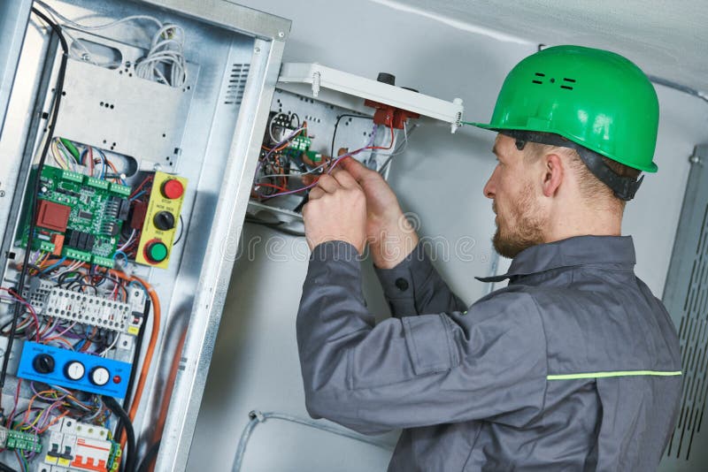 De elektricien maakt onderhoud in motorruimte van lift royalty-vrije stock afbeeldingen De elektricien maakt onderhoud in motorruimte van lift royalty-vrije stock afbeeldingen