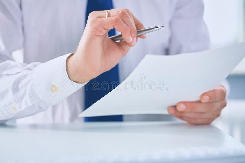 De ernstige bedrijfsmens die aan documenten werkt en maakt nota's met een penclose-up royalty-vrije stock foto's De ernstige bedrijfsmens die aan documenten werkt en maakt nota's met een penclose-up royalty-vrije stock foto's