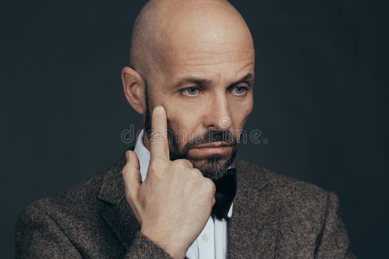 De ernstige midden oude mens met een effen gezichtsuitdrukking kleedde zich in het toevallige stellen op een donkergrijze achterg stock afbeeldingen De ernstige midden oude mens met een effen gezichtsuitdrukking kleedde zich in het toevallige stellen op een donkergrijze achterg stock afbeeldingen