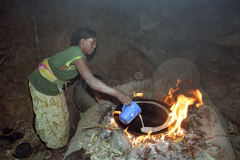 ETHIOPIA, Oromia, village Chancho Gaba Robi: Oromo woman, largest ethnic population group in Ethiopia, fry, bake on the fire in the kitchen of her home the staple food, or Ethiopian national dish injera. Made from the grain teff, a kind of pancake. Cooking is the most important domestic work of rural women. Most of her daily life consists of preparing food. The grain teff seems to have high nutritional values. Life and live, housing and living of Ethiopian. The fiery red flames come from under the baking sheet and the kitchen is full of smoke. ETHIOPIA, Oromia, village Chancho Gaba Robi: Oromo woman, largest ethnic population group in Ethiopia, fry, bake on the fire in the kitchen of her home the staple food, or Ethiopian national dish injera. Made from the grain teff, a kind of pancake. Cooking is the most important domestic work of rural women. Most of her daily life consists of preparing food. The grain teff seems to have high nutritional values. Life and live, housing and living of Ethiopian. The fiery red flames come from under the baking sheet and the kitchen is full of smoke.