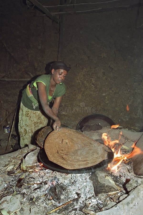 ETHIOPIA, Oromia, village Chancho Gaba Robi: Oromo woman, largest ethnic population group in Ethiopia, fry, bake on the fire in the kitchen of her home the staple food, or Ethiopian national dish injera. Made from the grain teff, a kind of pancake. Cooking is the most important domestic work of rural women. Most of her daily life consists of preparing food. The grain teff seems to have high nutritional values. Life and live, housing and living of Ethiopian. The fiery red flames come from under the baking sheet and the kitchen is full of smoke. ETHIOPIA, Oromia, village Chancho Gaba Robi: Oromo woman, largest ethnic population group in Ethiopia, fry, bake on the fire in the kitchen of her home the staple food, or Ethiopian national dish injera. Made from the grain teff, a kind of pancake. Cooking is the most important domestic work of rural women. Most of her daily life consists of preparing food. The grain teff seems to have high nutritional values. Life and live, housing and living of Ethiopian. The fiery red flames come from under the baking sheet and the kitchen is full of smoke.