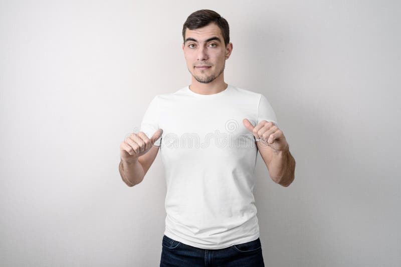 De Europese mens met een zeker gezicht toont witte lege t-shirt stock fotografie De Europese mens met een zeker gezicht toont witte lege t-shirt stock fotografie