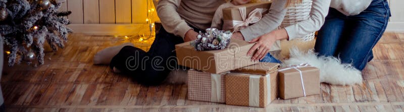 De familie dichtbij een open haard en een Kerstboom ontleedt giften zittend op de vloer de familie dichtbij de Kerstboom, koester stock fotografie De familie dichtbij een open haard en een Kerstboom ontleedt giften zittend op de vloer de familie dichtbij de Kerstboom, koester stock fotografie