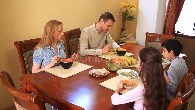 De familie dineert thuis in de eetkamer Kinderentieners, tweelingen en hun ouders