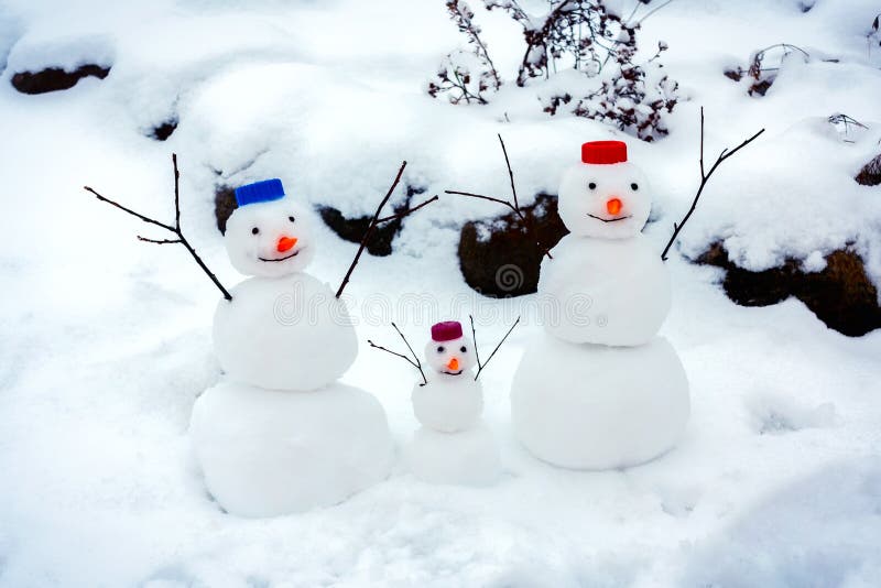 De familie van vrolijke sneeuwmannen verheugt zich bij de aankomst van de winter en de eerste sneeuw royalty-vrije stock foto De familie van vrolijke sneeuwmannen verheugt zich bij de aankomst van de winter en de eerste sneeuw royalty-vrije stock foto