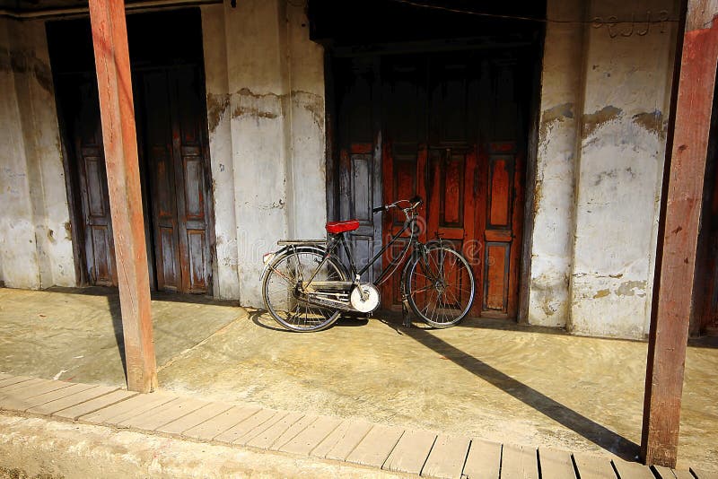 De fiets bij de oude houten deur wordt geparkeerd die stock foto De fiets bij de oude houten deur wordt geparkeerd die stock foto
