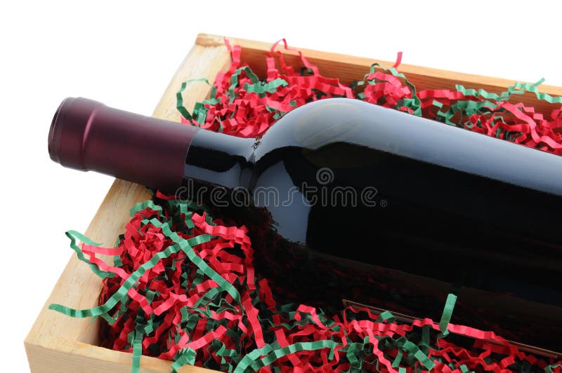 Closeup of a red wine bottle in a wood shipping crate with shredded filler paper in Christmas Holiday colors. Horizontal format isolated on a white background. Closeup of a red wine bottle in a wood shipping crate with shredded filler paper in Christmas Holiday colors. Horizontal format isolated on a white background.