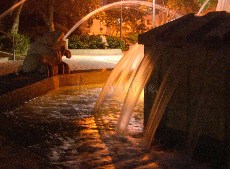 De fontein bespuitend water van het kikkersstandbeeld bij nacht in gele warme lichten in het park van Holon Herzel royalty-vrije stock afbeeldingen De fontein bespuitend water van het kikkersstandbeeld bij nacht in gele warme lichten in het park van Holon Herzel royalty-vrije stock afbeeldingen