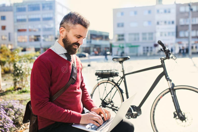 De forens van de Hipsterzakenman met fiets op de manier om in stad te werken, die laptop met behulp van stock afbeeldingen De forens van de Hipsterzakenman met fiets op de manier om in stad te werken, die laptop met behulp van stock afbeeldingen