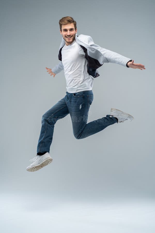 De foto van gemiddelde lengte van de grappige mens in toevallige t-shirt, blazer en jeans die of in lucht lopen springen isoleerd royalty-vrije stock foto's De foto van gemiddelde lengte van de grappige mens in toevallige t-shirt, blazer en jeans die of in lucht lopen springen isoleerd royalty-vrije stock foto's