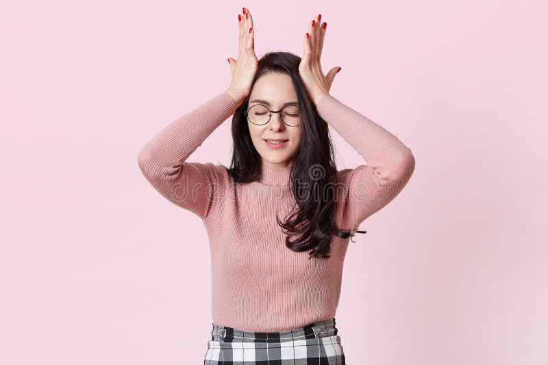 De foto van ontevreden jonge donkere haired vrouw, houdt hand op voorhoofd, klemt tanden, gekleed in aanbiddelijke sweater en rok royalty-vrije stock afbeelding De foto van ontevreden jonge donkere haired vrouw, houdt hand op voorhoofd, klemt tanden, gekleed in aanbiddelijke sweater en rok royalty-vrije stock afbeelding
