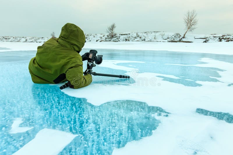 De fotograaf neemt beeldenbellen van methaangas in duidelijk ijsmeer Baikal worden bevroren, Rusland dat