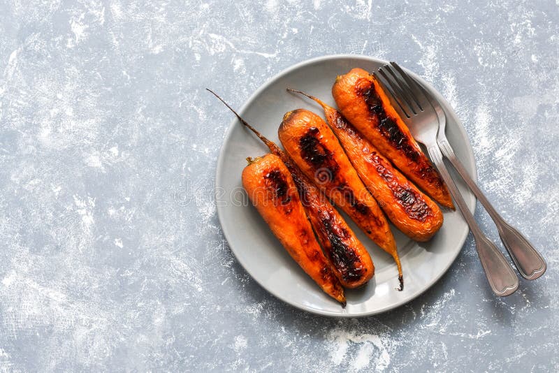 De gebakken wortelen worden gediend op een grijze plaat Vegetarisch voedsel Vlak leg van de exemplaarruimte royalty-vrije stock fotografie De gebakken wortelen worden gediend op een grijze plaat Vegetarisch voedsel Vlak leg van de exemplaarruimte royalty-vrije stock fotografie