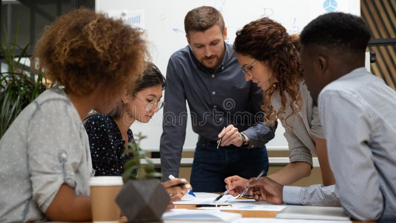 De geconcentreerde multi-etnische zakenmensen werken samen bespreken papierwerk bij vergadering stock afbeelding De geconcentreerde multi-etnische zakenmensen werken samen bespreken papierwerk bij vergadering stock afbeelding