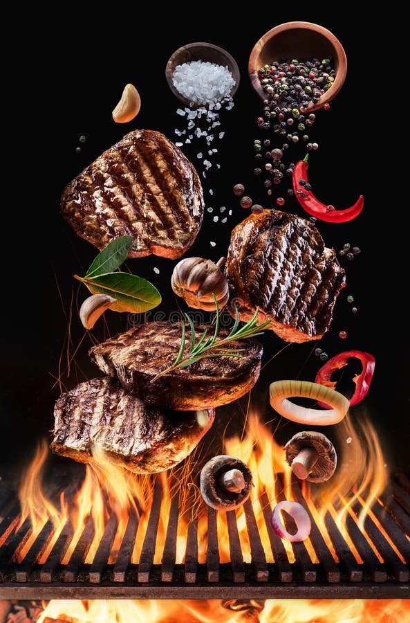 De gekookte rundvleeslapjes vlees met groenten en kruiden vliegen over de opvlammende brand van de grillbarbecue