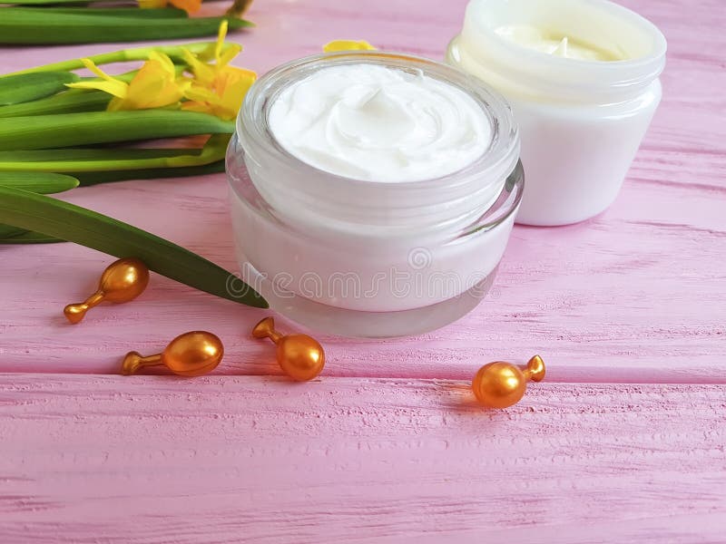 De gele narcissen romen kosmetische gezichts het maskercapsules van het luchtbeschermingsproduct op roze houten natuurlijk af stock foto De gele narcissen romen kosmetische gezichts het maskercapsules van het luchtbeschermingsproduct op roze houten natuurlijk af stock foto