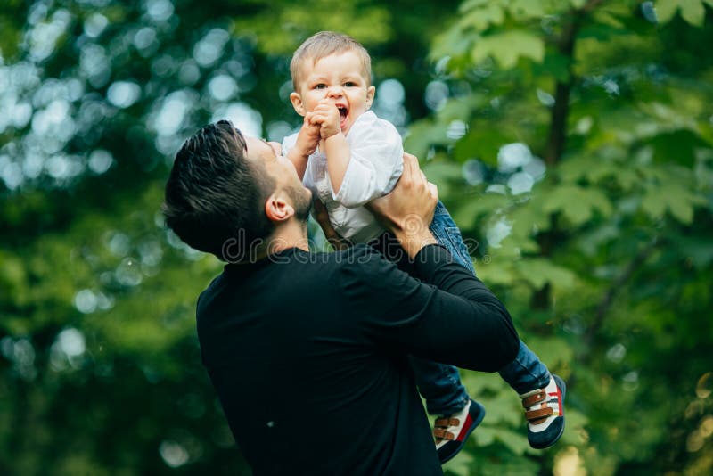 De gelukkige blije vader die pret hebben werpt in de lucht omhoog zijn klein kind royalty-vrije stock foto De gelukkige blije vader die pret hebben werpt in de lucht omhoog zijn klein kind royalty-vrije stock foto