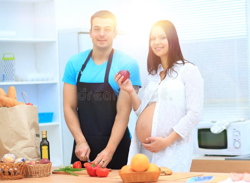 De gelukkige echtgenoot maakt Ontbijt voor zijn zwangere vrouw stock afbeelding De gelukkige echtgenoot maakt Ontbijt voor zijn zwangere vrouw stock afbeelding