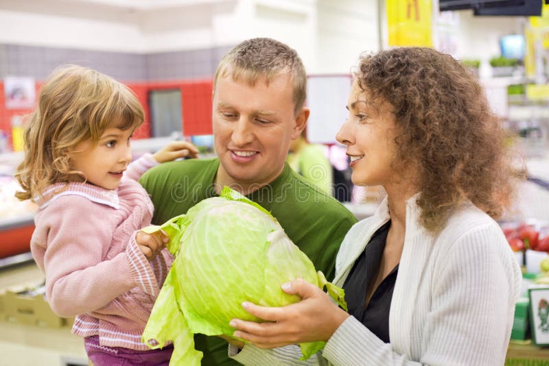 De gelukkige familie met meisje koopt kool in supermarkt royalty-vrije stock foto's De gelukkige familie met meisje koopt kool in supermarkt royalty-vrije stock foto's