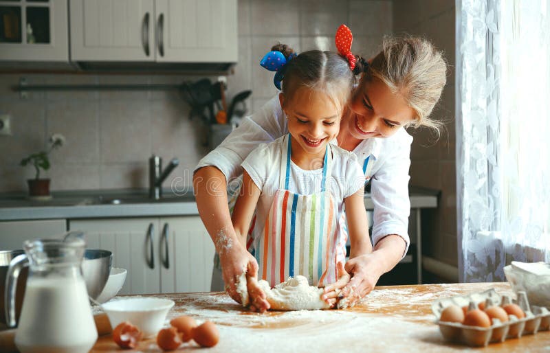 De gelukkige de familiemoeder en dochter bakken het kneden deeg in keuken