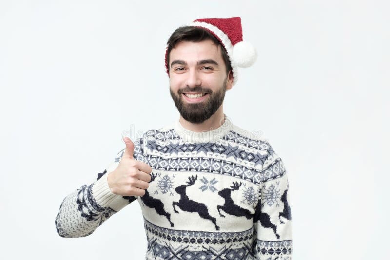De gelukkige grappige mens in rode Kerstmishoed toont duimen en goed geluk royalty-vrije stock afbeelding De gelukkige grappige mens in rode Kerstmishoed toont duimen en goed geluk royalty-vrije stock afbeelding