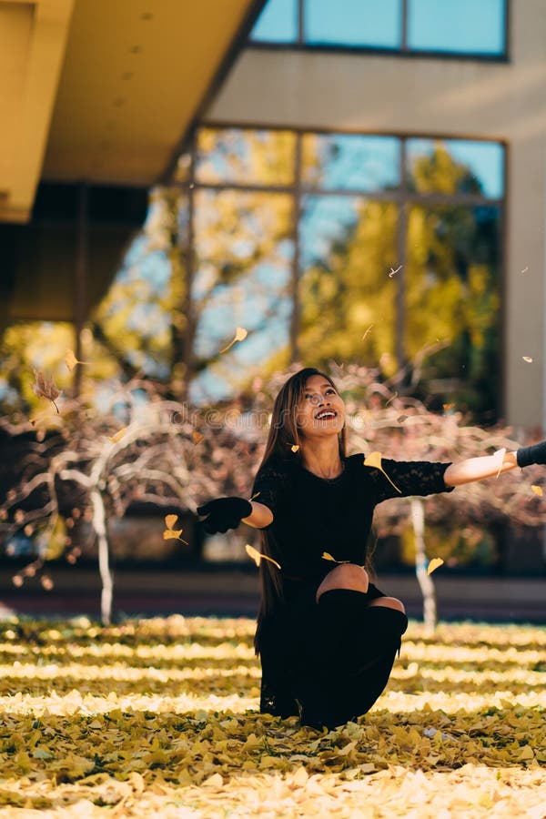 De gelukkige jonge vrouw in park op zonnige de herfstdag, het lachen, het spelen gaat weg Vrolijk mooi meisje in zwarte retro fas stock foto De gelukkige jonge vrouw in park op zonnige de herfstdag, het lachen, het spelen gaat weg Vrolijk mooi meisje in zwarte retro fas stock foto
