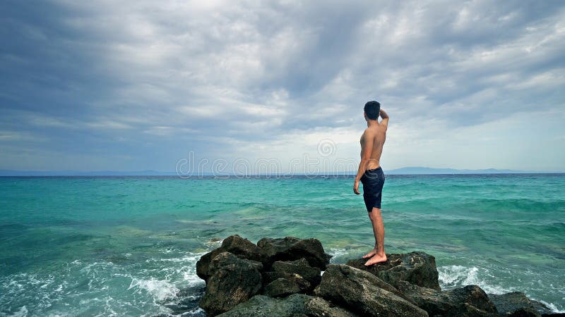De gelukkige jongelui past tiener status op rotsen en het navigeren aan horizon genietend van vakantie stock foto De gelukkige jongelui past tiener status op rotsen en het navigeren aan horizon genietend van vakantie stock foto