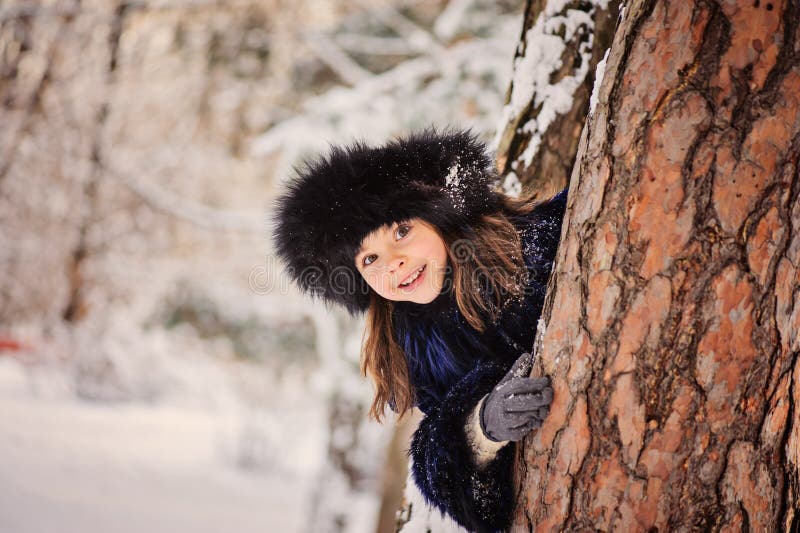 De gelukkige kindmeisje het spelen huid - en - zoekt in de winterbos royalty-vrije stock fotografie De gelukkige kindmeisje het spelen huid - en - zoekt in de winterbos royalty-vrije stock fotografie