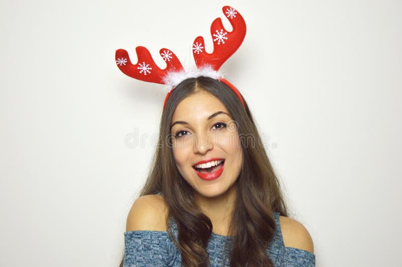 De gelukkige mooie vrouw met rendierhoornen op haar hoofd bekijkt camera op witte achtergrond De vakantie van Kerstmis stock foto De gelukkige mooie vrouw met rendierhoornen op haar hoofd bekijkt camera op witte achtergrond De vakantie van Kerstmis stock foto